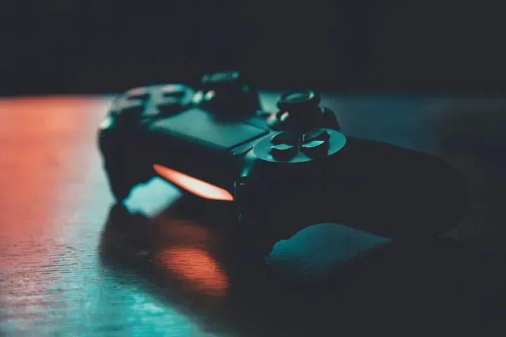 Manette de jeu vidéo éclairée dans la pénombre, métaphore du pilotage de l'informatique
